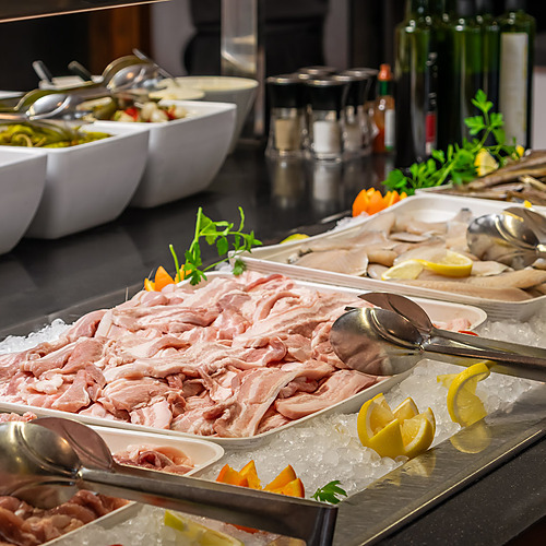 Buffet display at a hotel restaurant featuring raw meats, fish, and vegetables for ESTIVAL: D Altafulla.