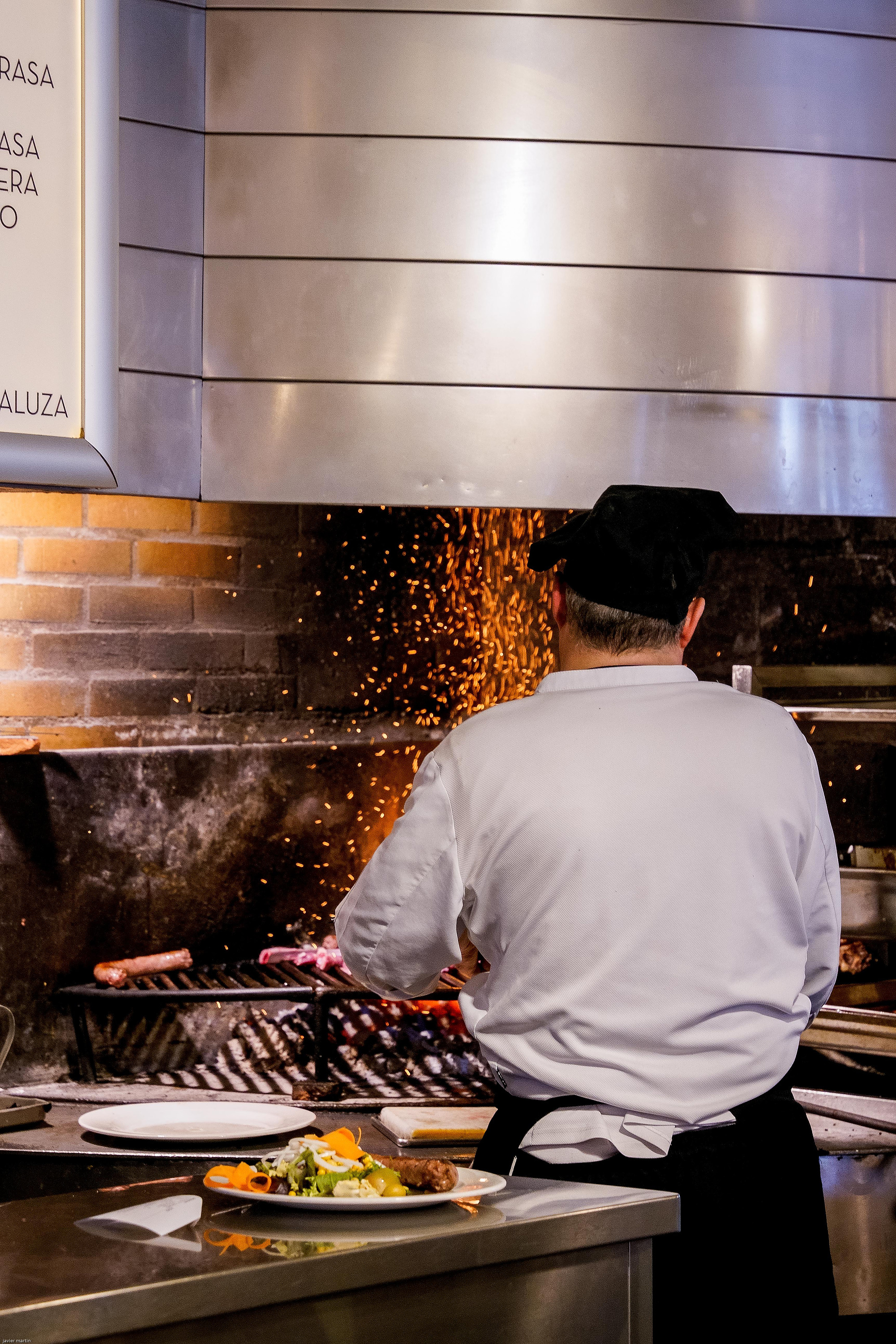 Dos chefs preparan comida en una estación de cocina abierta o tipo buffet en un restaurante.