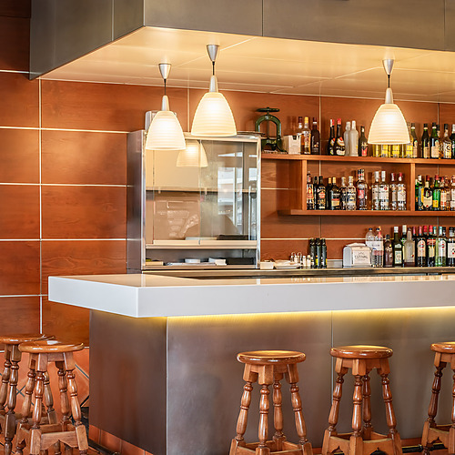 Bar stools and shelves stocked with bottles at a hotel ESTIVAL: D Altafulla.