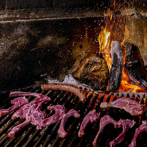 Rack of lamb and sausage grilling over a roaring fire at ESTIVAL: D Altafulla.