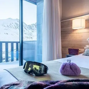 um quarto com uma cama e uma janela com montanhas ao fundo