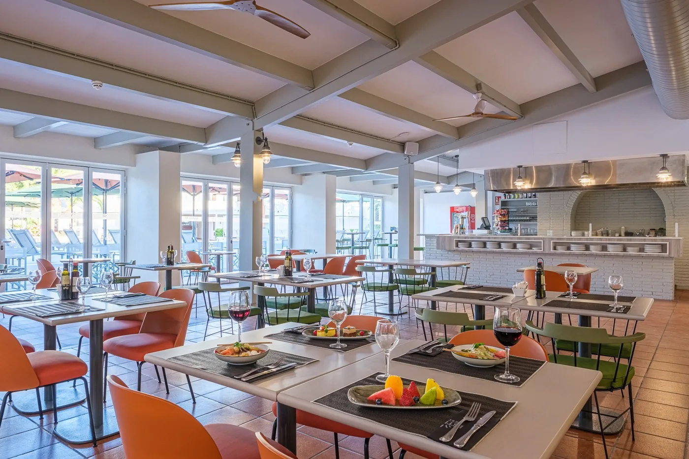 Elegante restaurante ESTIVAL: Oassium Hotel, mesas puestas, sillas naranjas.