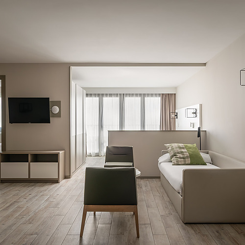 Habitación ESTIVAL: Corporativa, cama doble con oso de peluche y sillón.