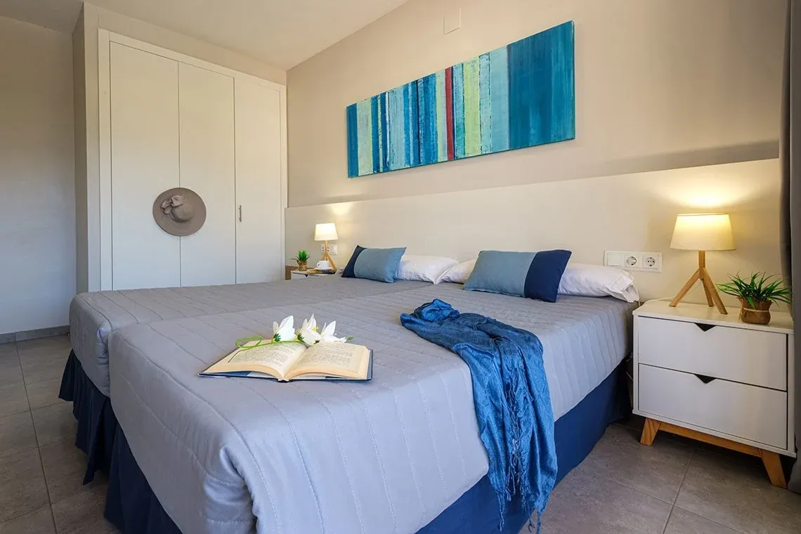 Modernes Doppelzimmer mit Doppelbetten, blauem Akzent und Kunstwerk, ideal für Ihren ESTIVAL: Corporativa-Aufenthalt.