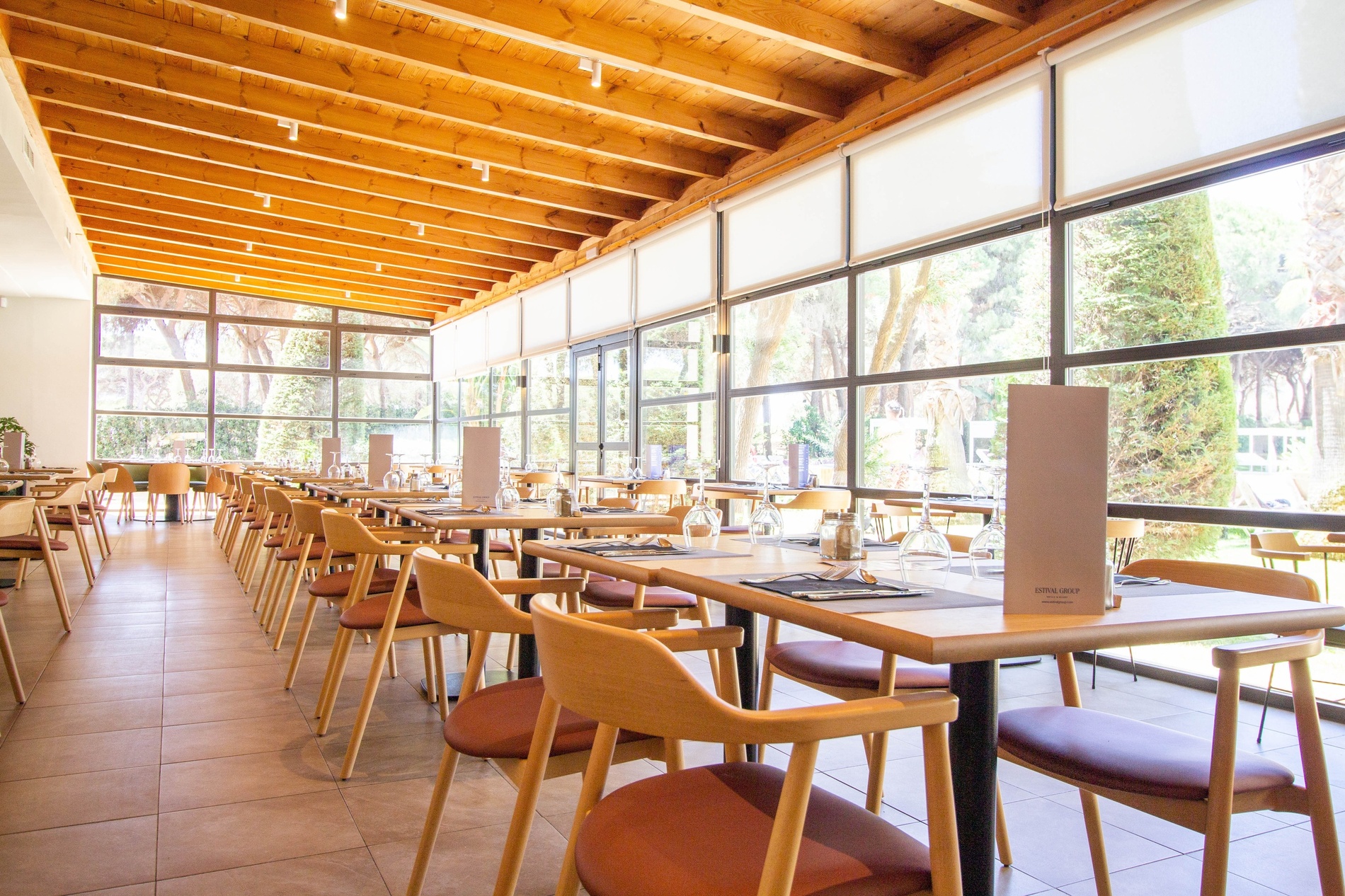 Comedor con grandes ventanales y vistas al jardín en Estival Isla Cristina 4* Superior.