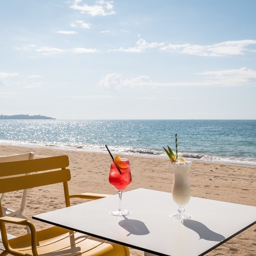 una mesa en la playa con dos bebidas en ella