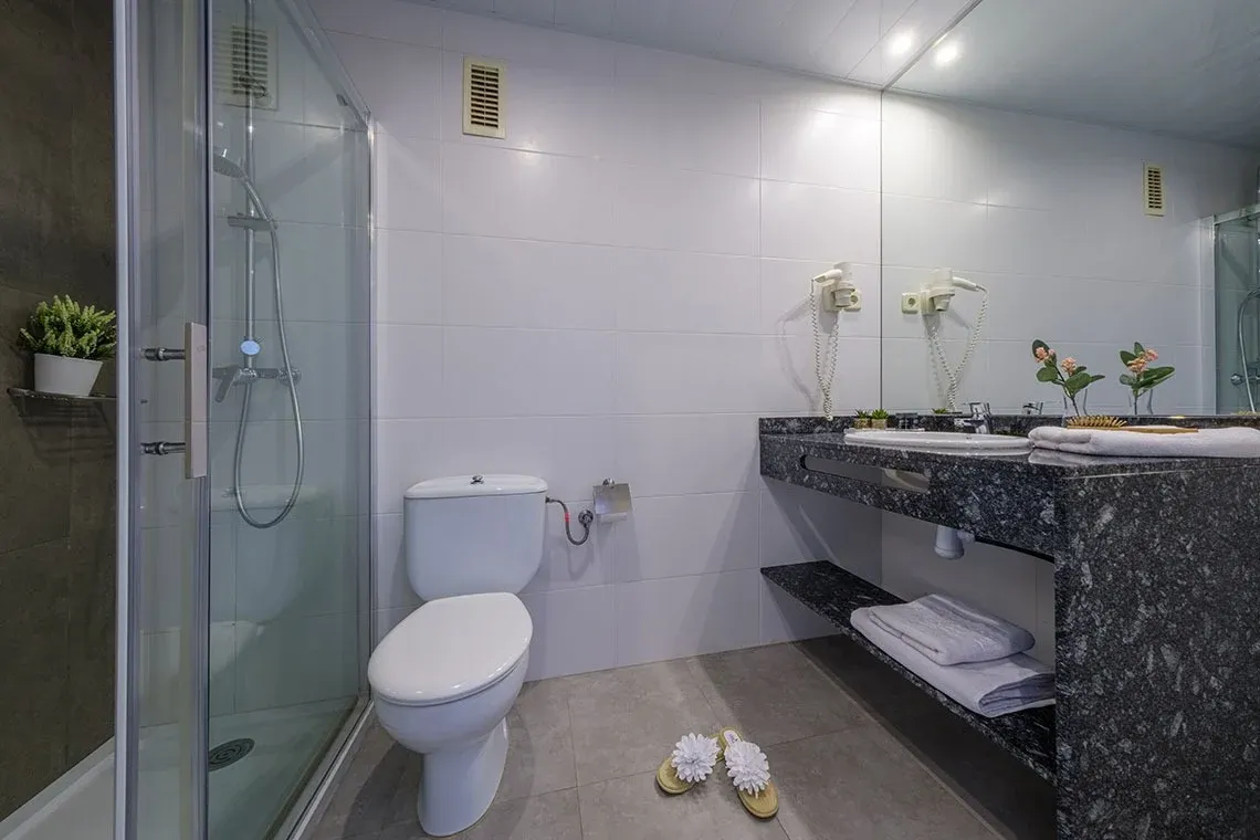 Modernes Badezimmer mit Dusche, WC und Waschbecken - Ihr ESTIVAL: Corporativa im Hotel.