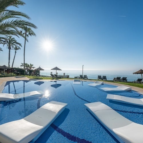 a large swimming pool surrounded by chairs and umbrellas