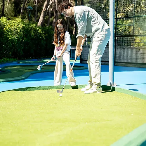 Un homme et une fille jouent au mini-golf à Estival Torre de la Mora.