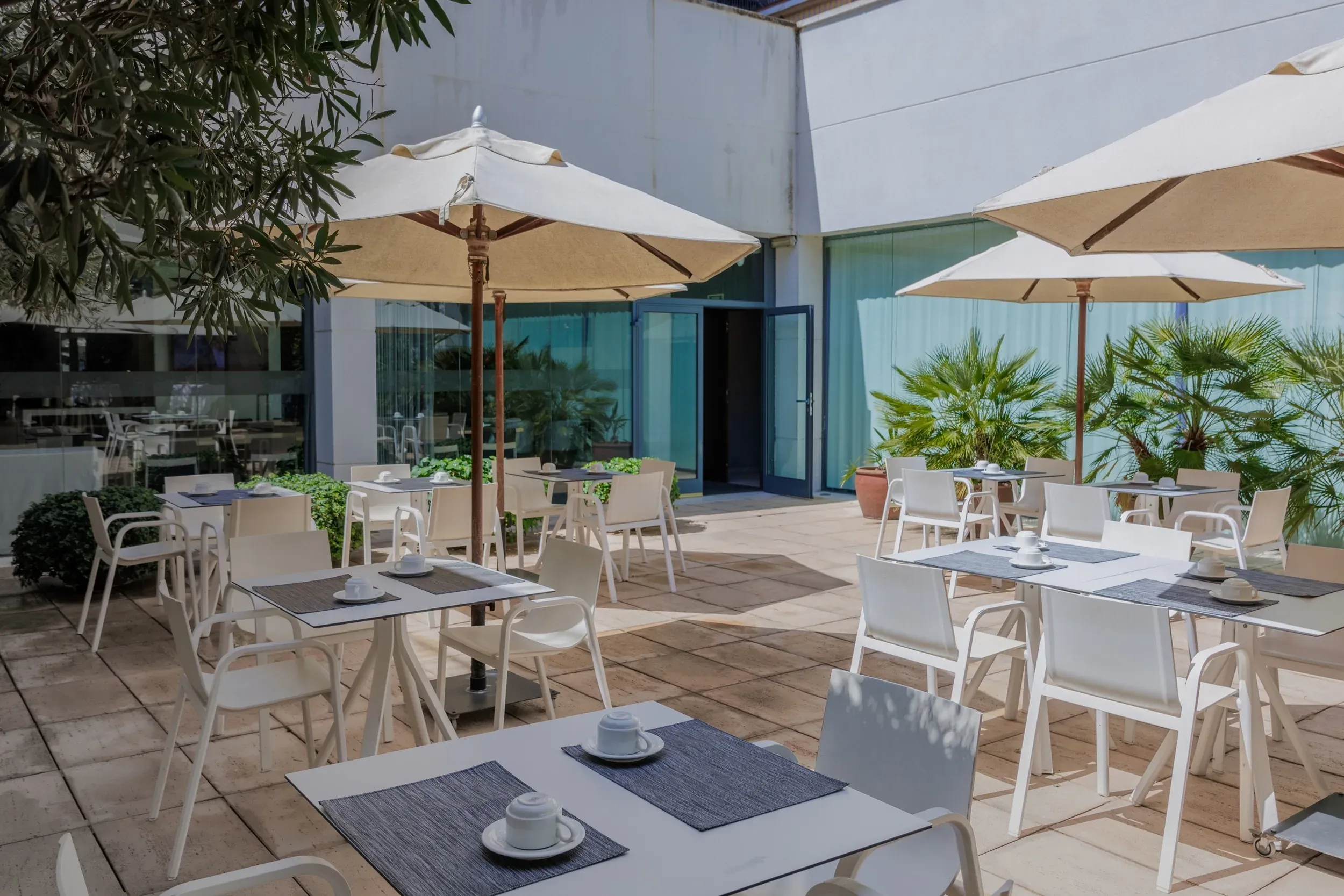 ESTIVAL: Corporative Terrasse mit Tischen und Stühlen unter Sonnenschirmen.