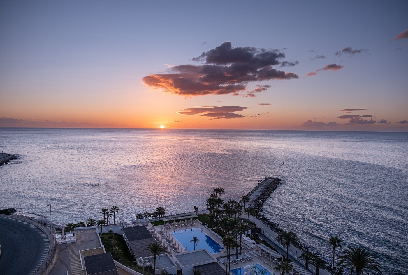 Sonnenuntergang über dem Ozean mit einem Pool im Vordergrund