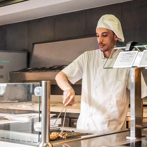 un cocinero prepara comida en una cocina con un cartel que dice 