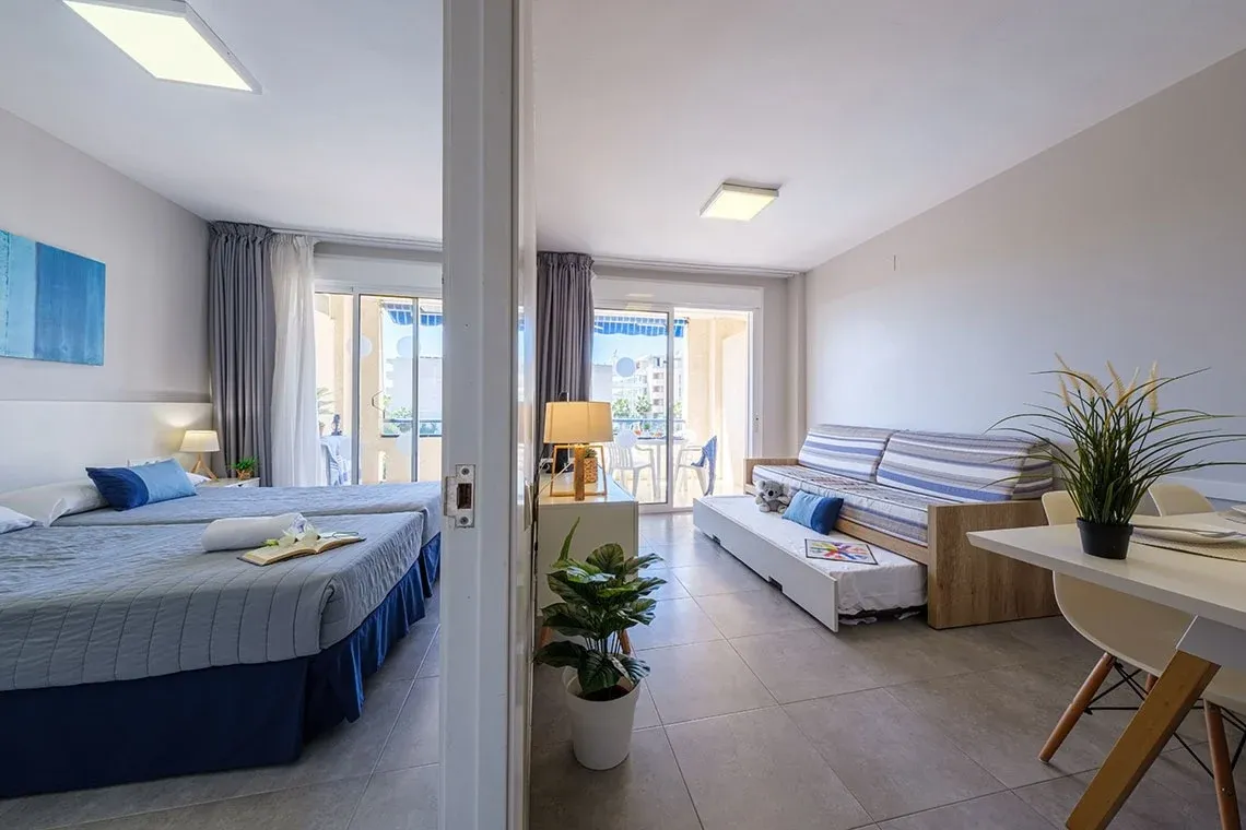 Helles Schlafzimmer mit zwei Betten und Wohnbereich mit SofaESTIVAL: Corporativa.