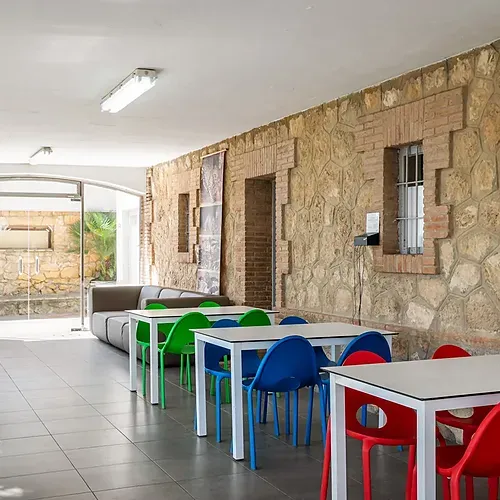 Espace commun avec tables et chaises colorées à Estival Torre de la Mora, Estival Group, Tarragone.