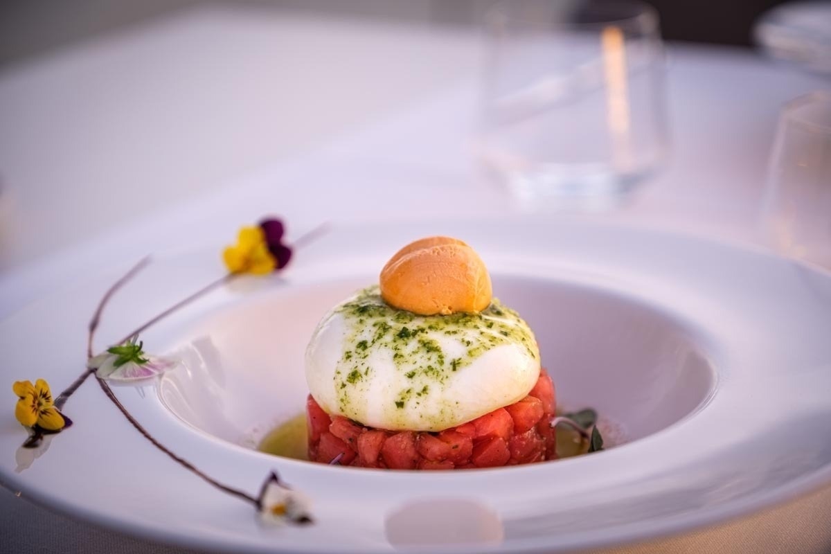 Gourmet burrata with tomato, herb dressing, and a delicate ice cream sphere. The Terrace | Estival Eldorado | Estival Group | Official Website.