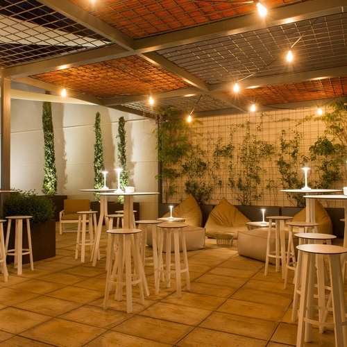 a patio area with tables and stools under a canopy