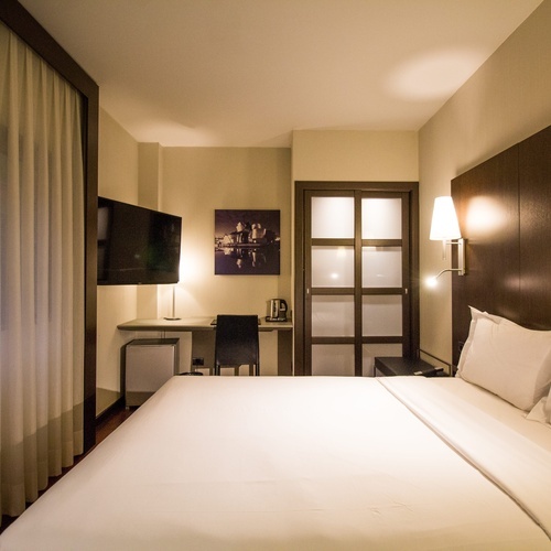 a hotel room with a bed a desk and a television