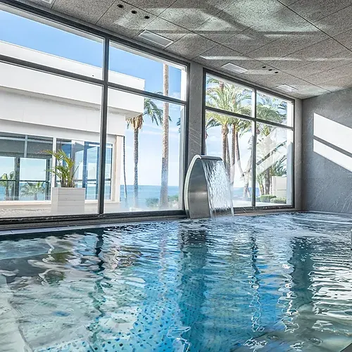 Indoor spa pool with waterfall and ocean view at Estival Torrequebrada Benalmádena, Estival Group.