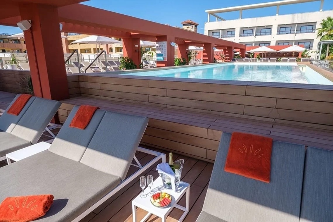 una piscina rodeada de sillas y una mesa con una botella de champán