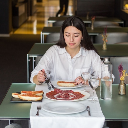 a woman sits at a table with plates of food on it