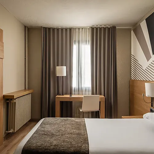 Modern hotel room with two beds, open closet, and mountain views. Hotel Sporting Andorra | Grandvalira Pas de la Casa | Official Web