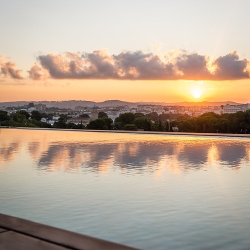 a sunset over a city with a swimming pool in the foreground