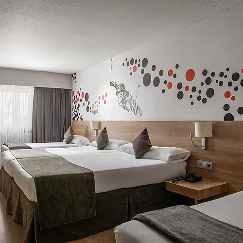 Modern hotel room with twin beds, TV, and desk. Hotel Sporting Andorra | Grandvalira Pas de la Casa | Official Web