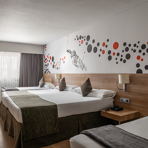Modern hotel room with twin beds, TV, and desk. Hotel Sporting Andorra | Grandvalira Pas de la Casa | Official Web