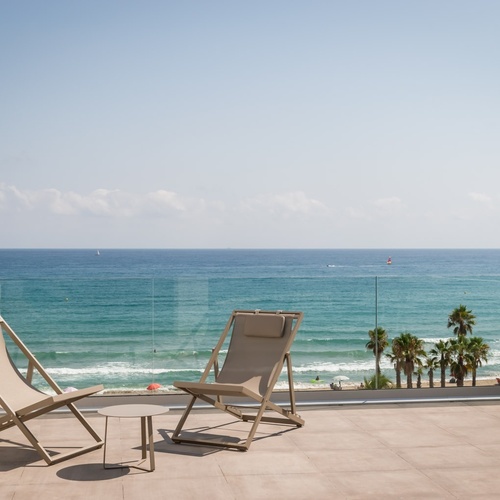 two chairs sit on a balcony overlooking the ocean