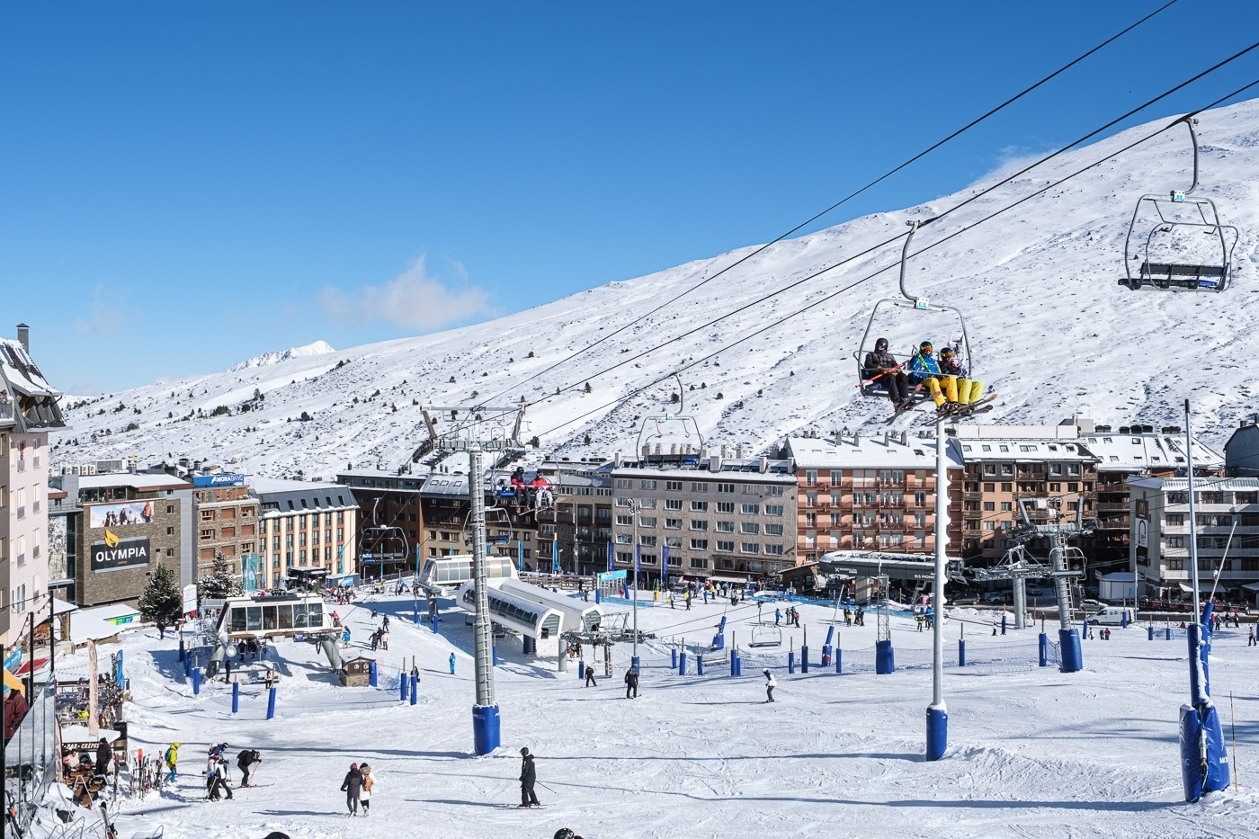 people on a ski lift in front of a building that says olympus