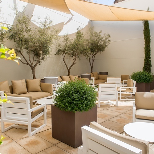 a patio with chairs and tables under an umbrella