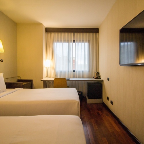 a hotel room with two beds and a flat screen tv