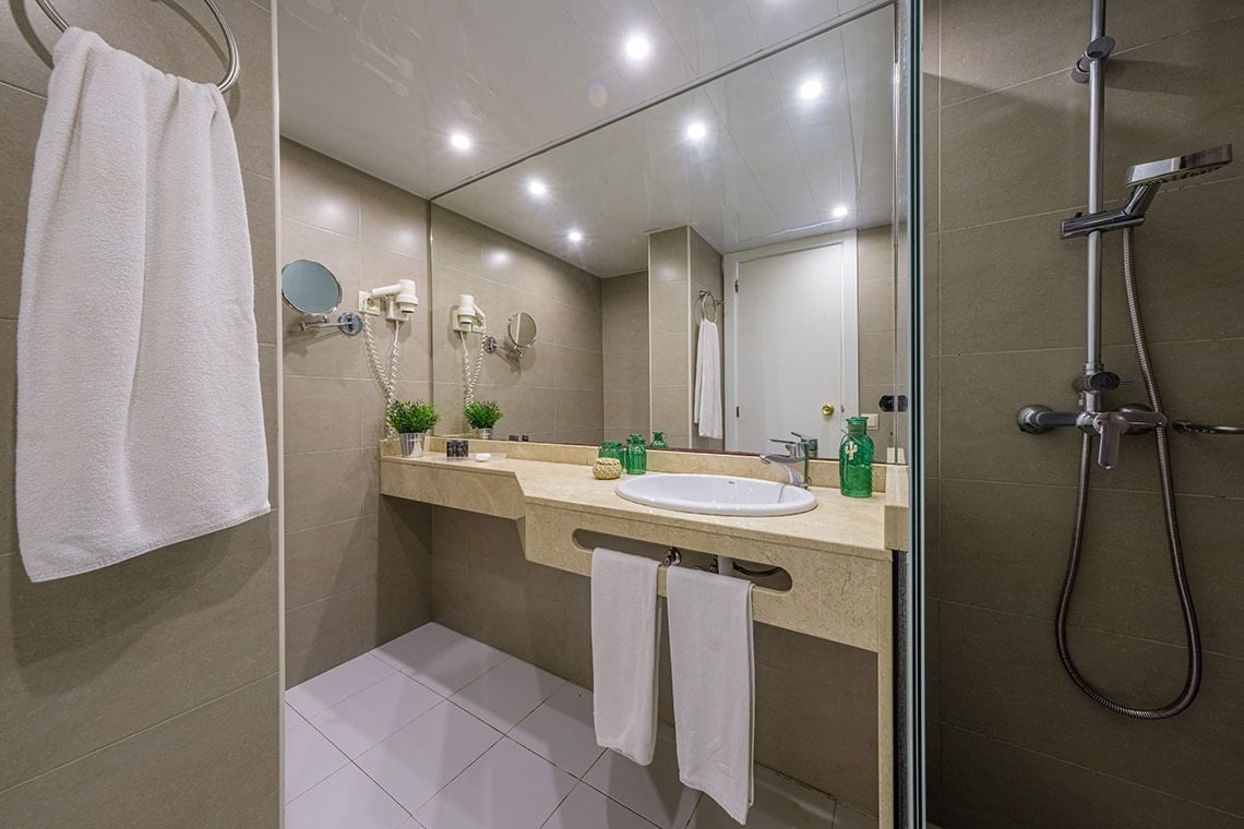 Modern Hotelbad mit Dusche und Waschbecken, Handtücher und Spiegel ESTIVAL: Corporativa.