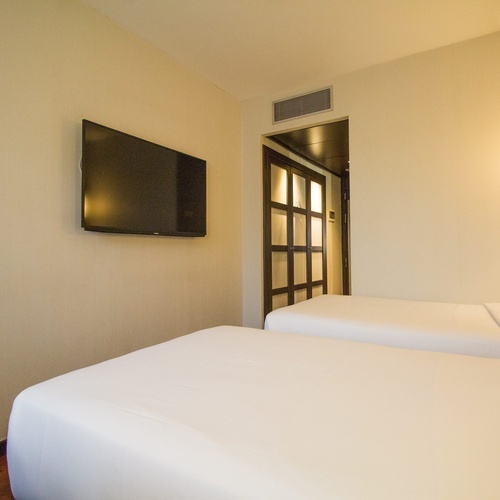 a hotel room with two beds and a flat screen tv