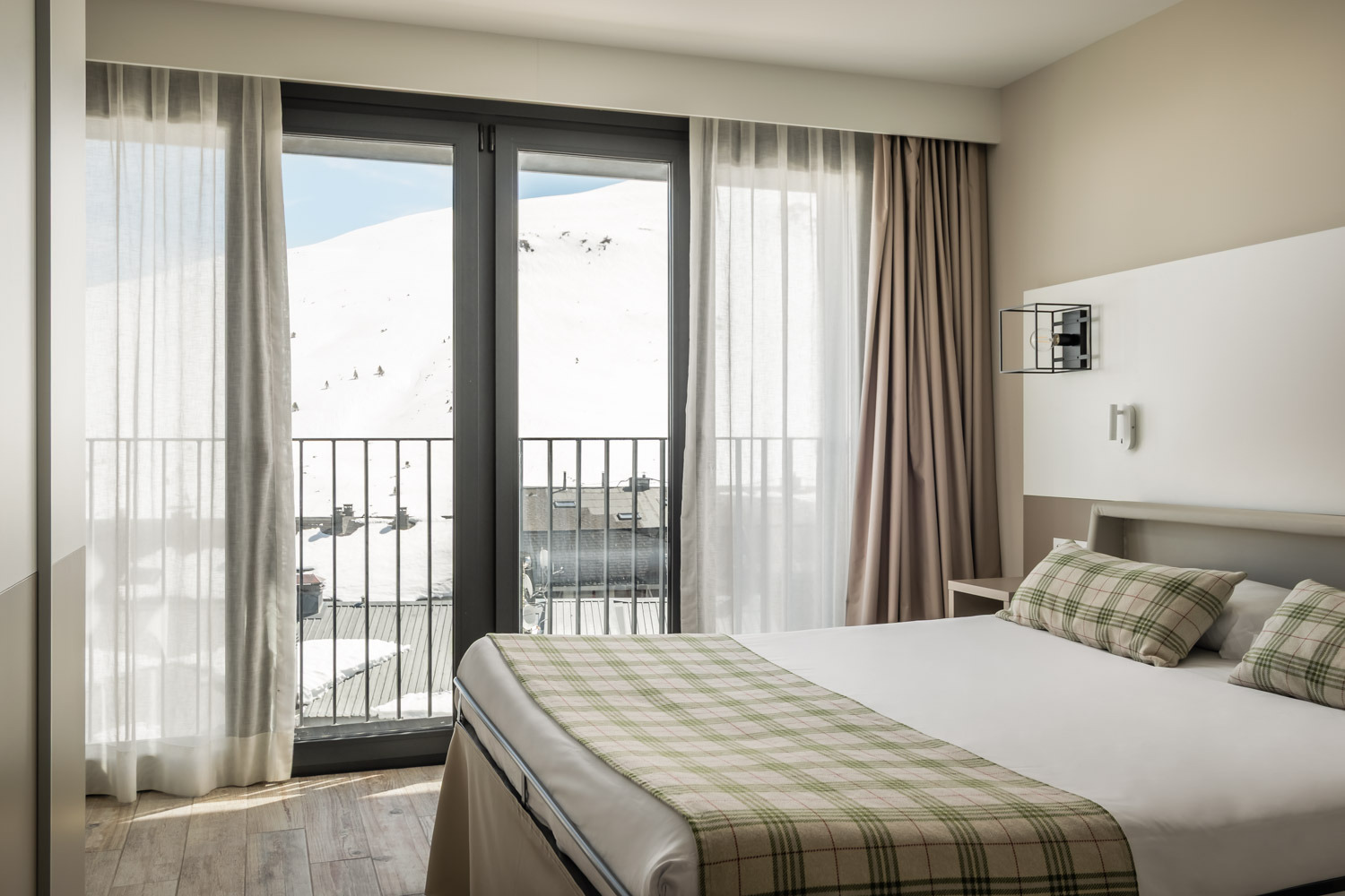 Modern hotel room with twin beds, wardrobe, and balcony view at Apartments Caribou Andorra | Summer Group.