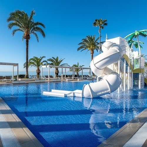a swimming pool with a water slide and palm trees in the background