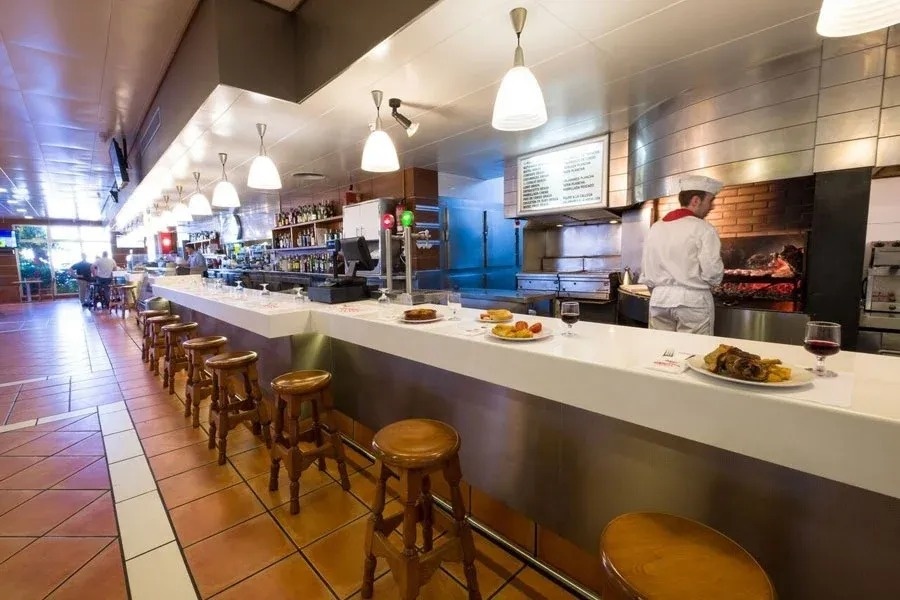 Bar intérieur avec tabourets et grill ouvert, parfait pour El Buffet d'Altafulla | Tarragone | Estival Group | Site Web Officiel.