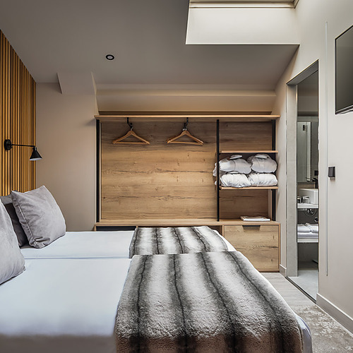 ESTIVAL: Modern bedroom with TV, open closet, and furry throw.