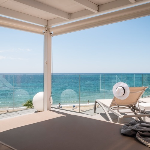 un balcón con sillas y una cama con vista al océano