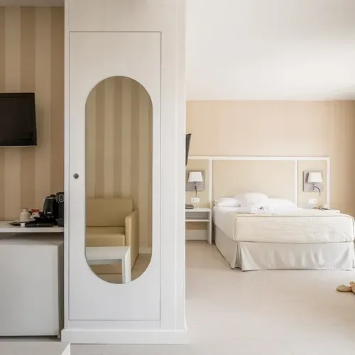 ESTIVAL: Corporate. Bright hotel room with bed, desk, and mirror.
