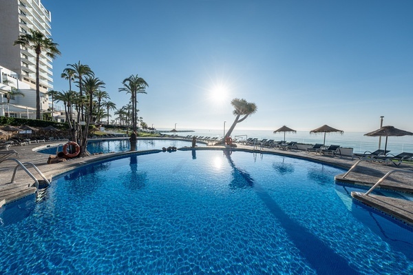 a large swimming pool surrounded by palm trees and umbrellas