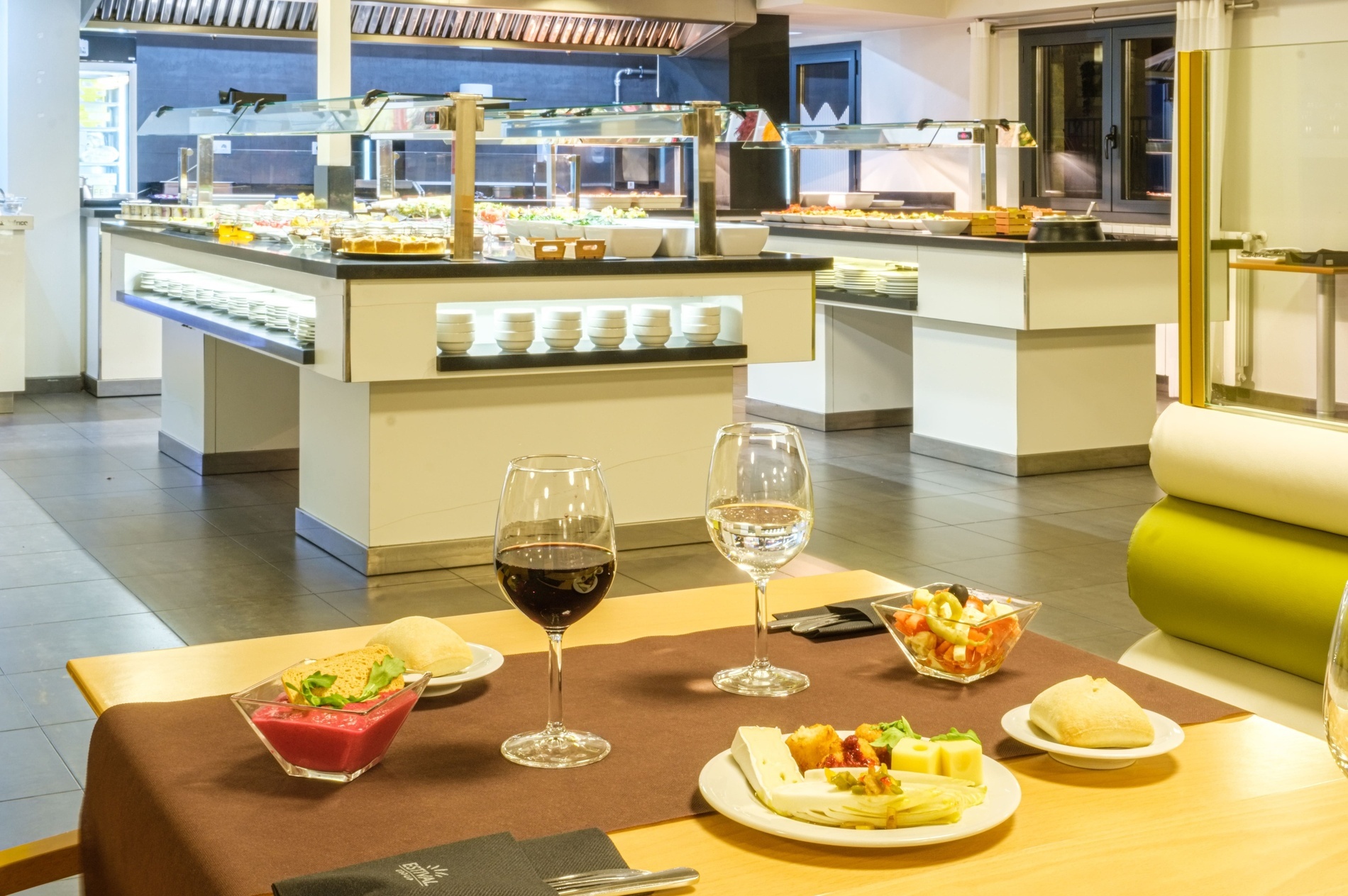 two glasses of wine sit on a table in front of a buffet