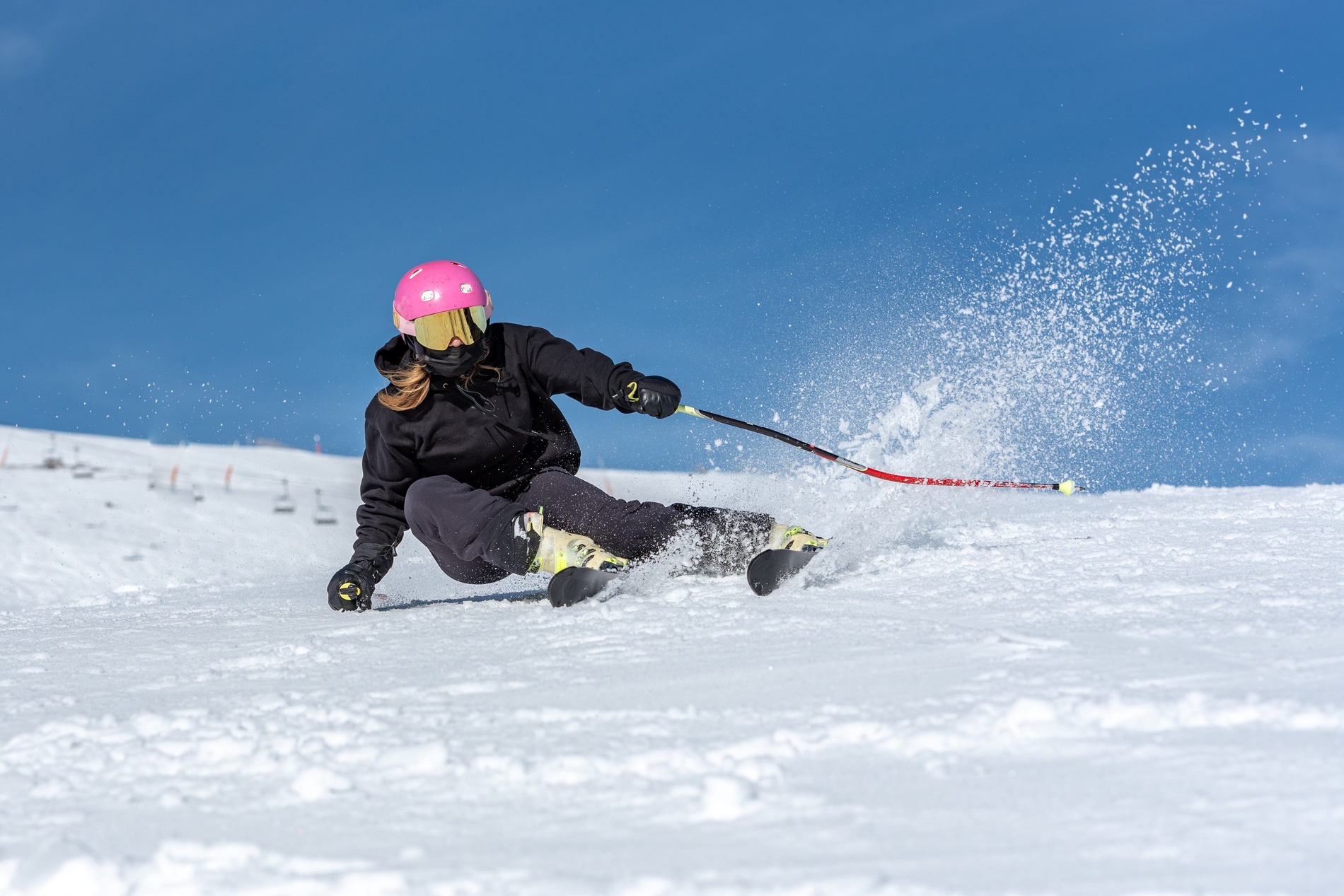 un skieur portant un casque rose et des lunettes de soleil s'élève sur une pente enneigée
