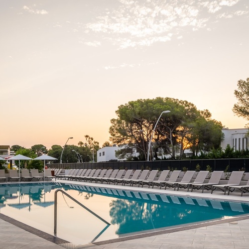 a large swimming pool surrounded by chairs and umbrellas