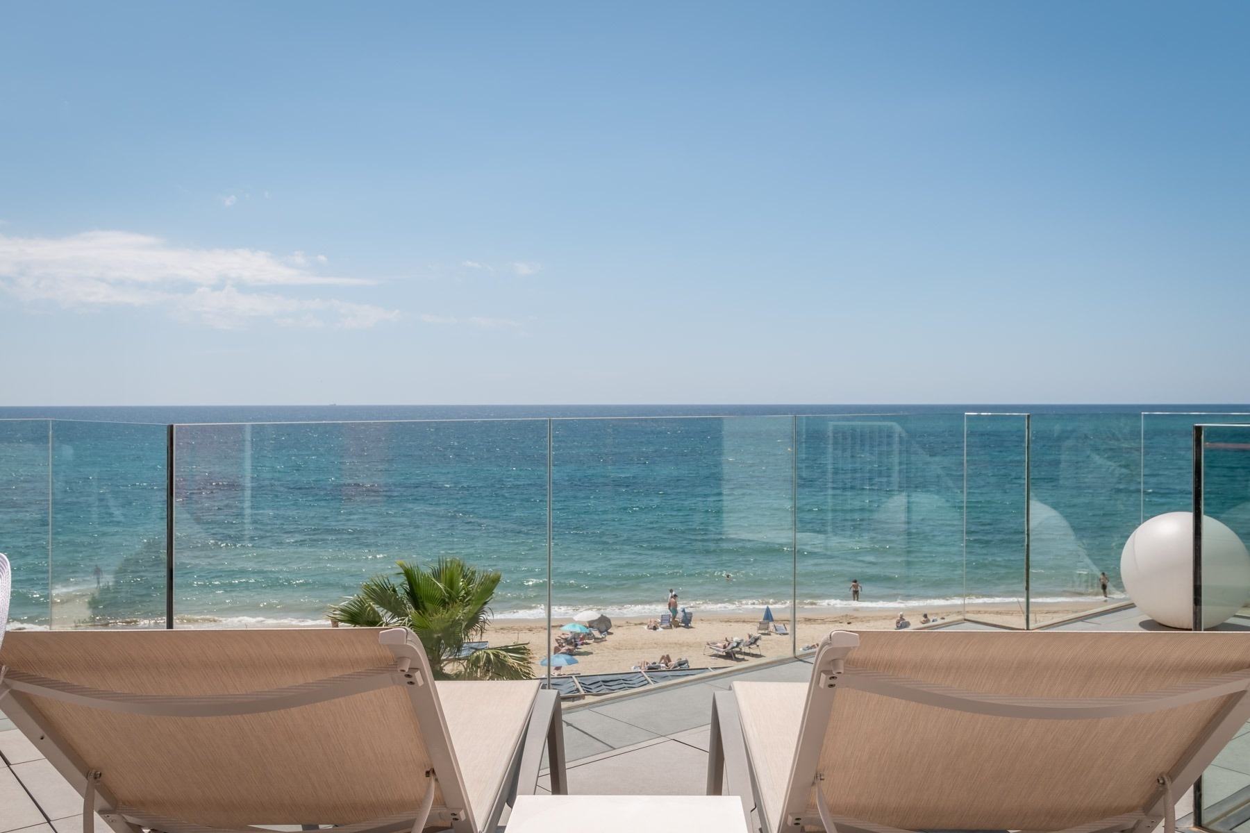 una vista del océano desde un balcón con muebles blancos