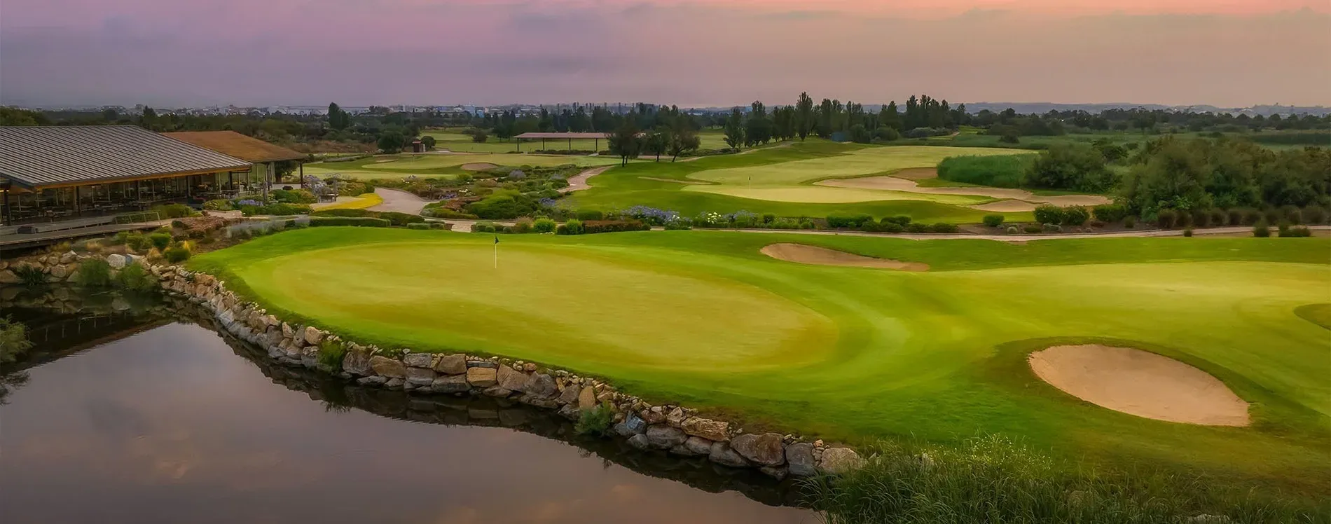 Golfplatz mit Restaurant, Wasser und Blick auf die Stadt. Erleben Sie Golf in Malaga, Tarragona und Huelva im Sommer.