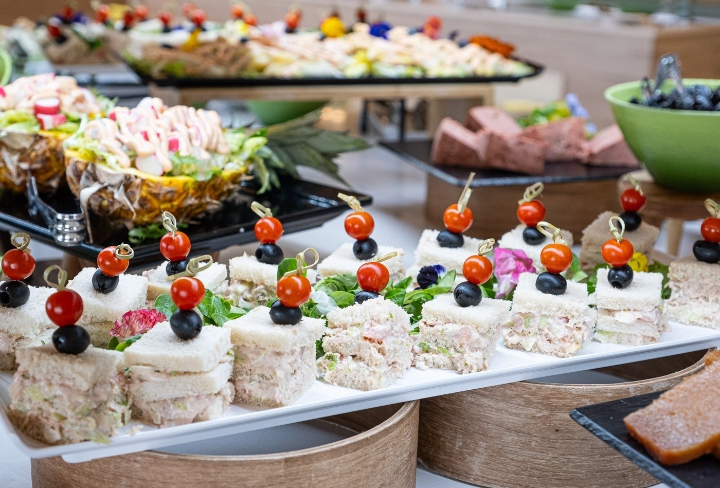 un buffet lleno de comida incluyendo sándwiches y tomates cherry