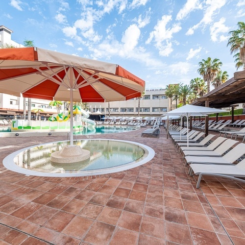 a swimming pool with a red and white umbrella in the middle