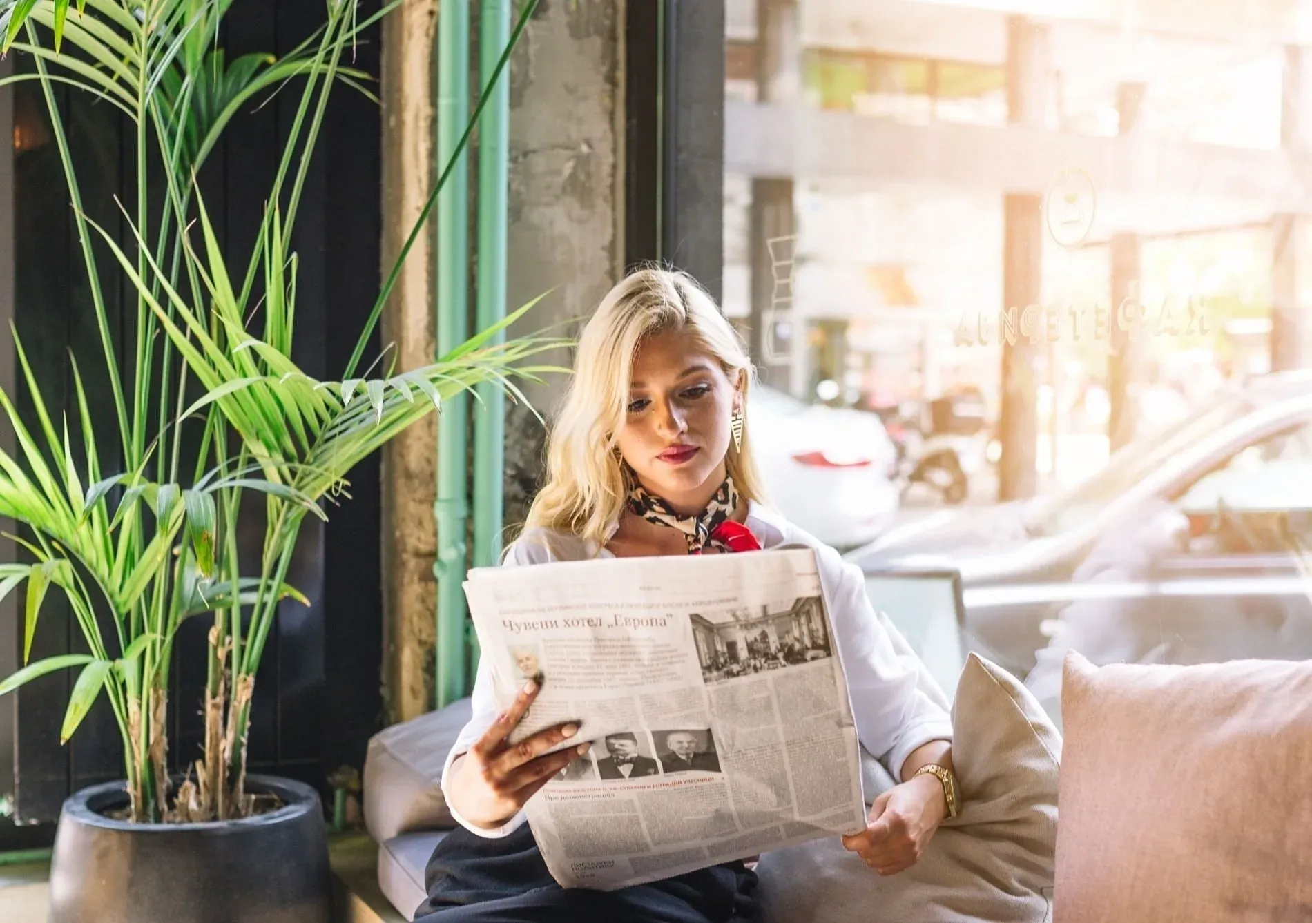 Femme blonde lisant un journal dans un café, découvrez-en plus sur le Blogue | Groupe Estival | Site officiel