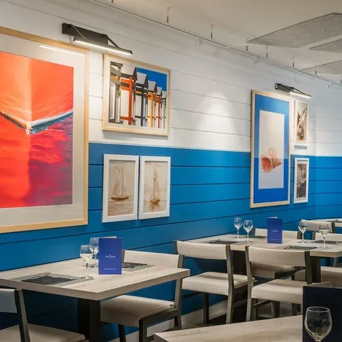 ESTIVAL: Corporativa dining area with nautical art and blue accents.